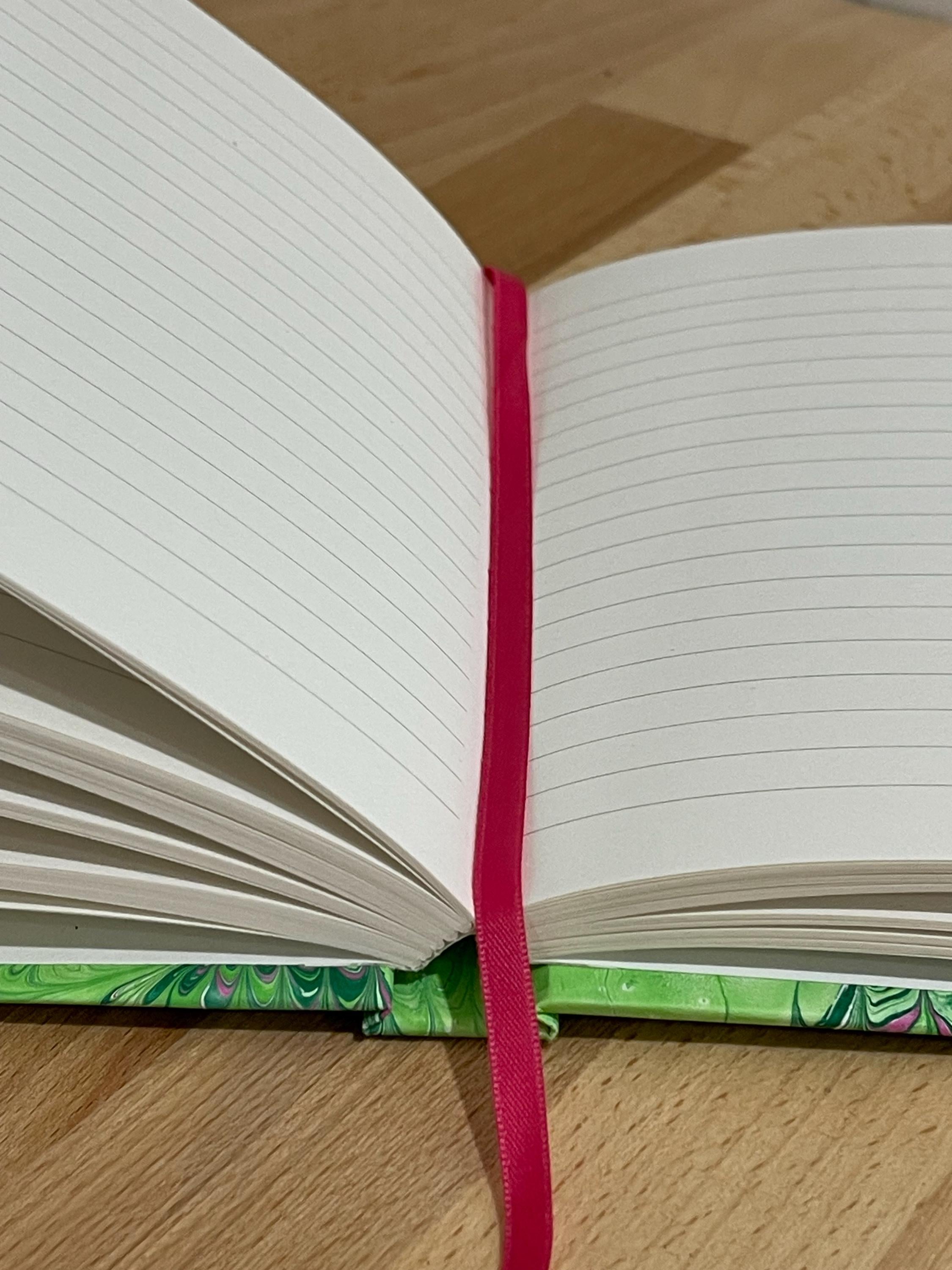 Hand marbled/painted notebook journal in a green and pink non pareil pattern with a pink book mark and recycled white lined pages