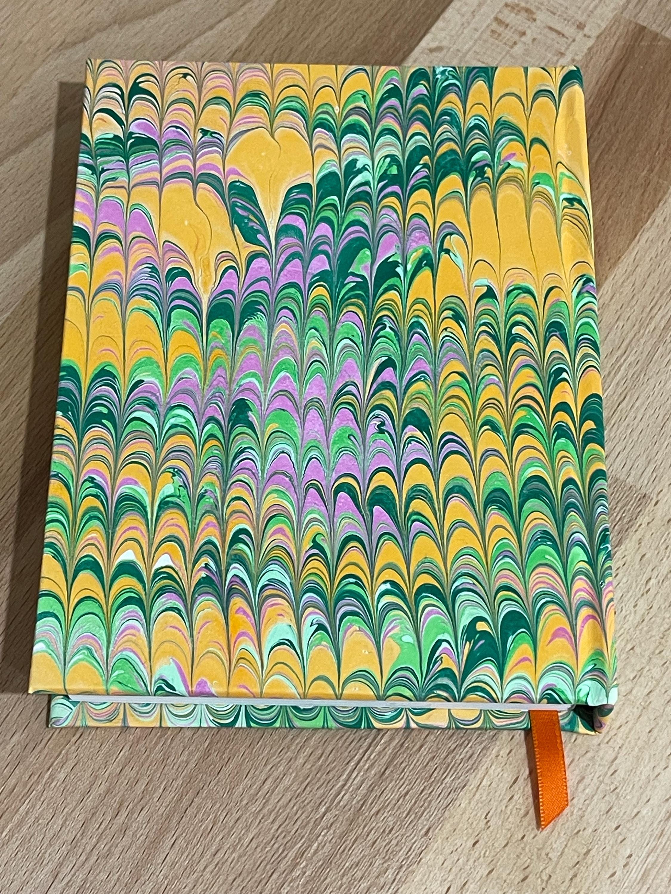 Hand marbled/painted notebook journal in a green and orange non pareil pattern with an orange book mark and recycled white lined pages