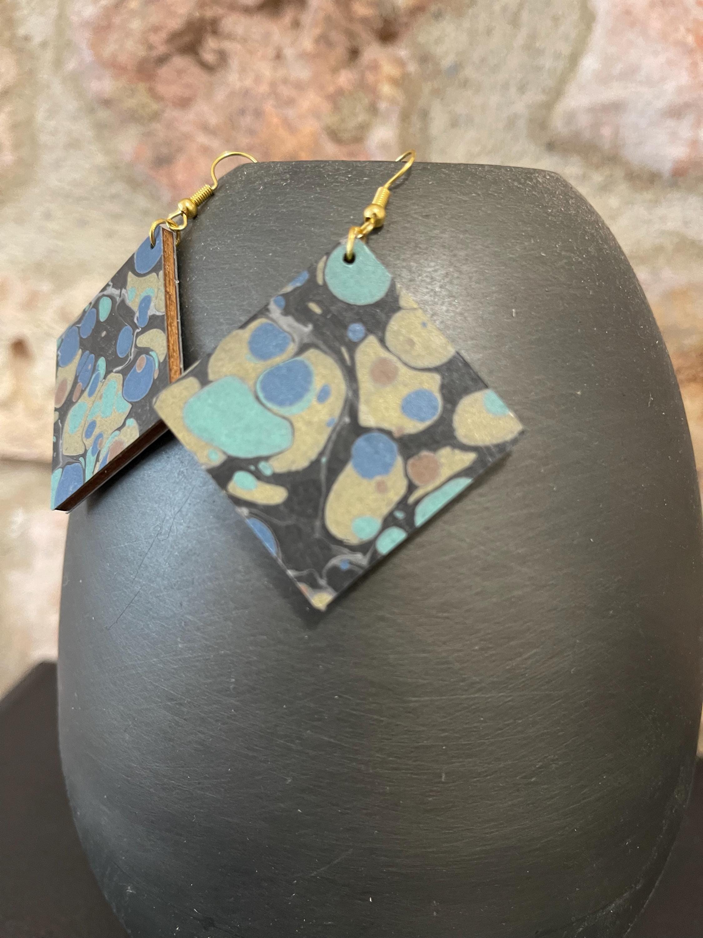 Unique square marbled dangle earrings with gold hyper allergenic hooks, stone pattern in gold, blue and green on a black background