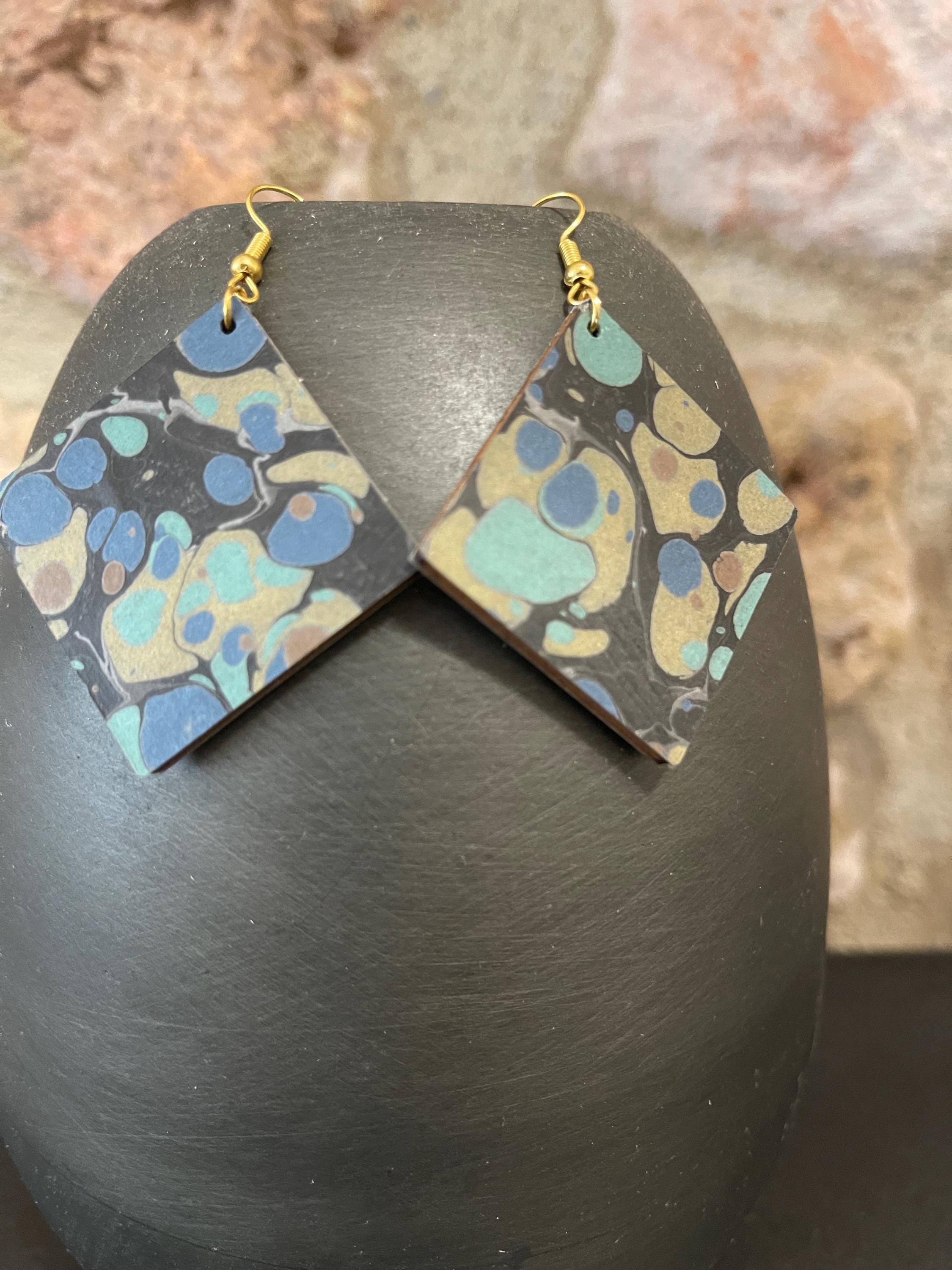 Unique square marbled dangle earrings with gold hyper allergenic hooks, stone pattern in gold, blue and green on a black background