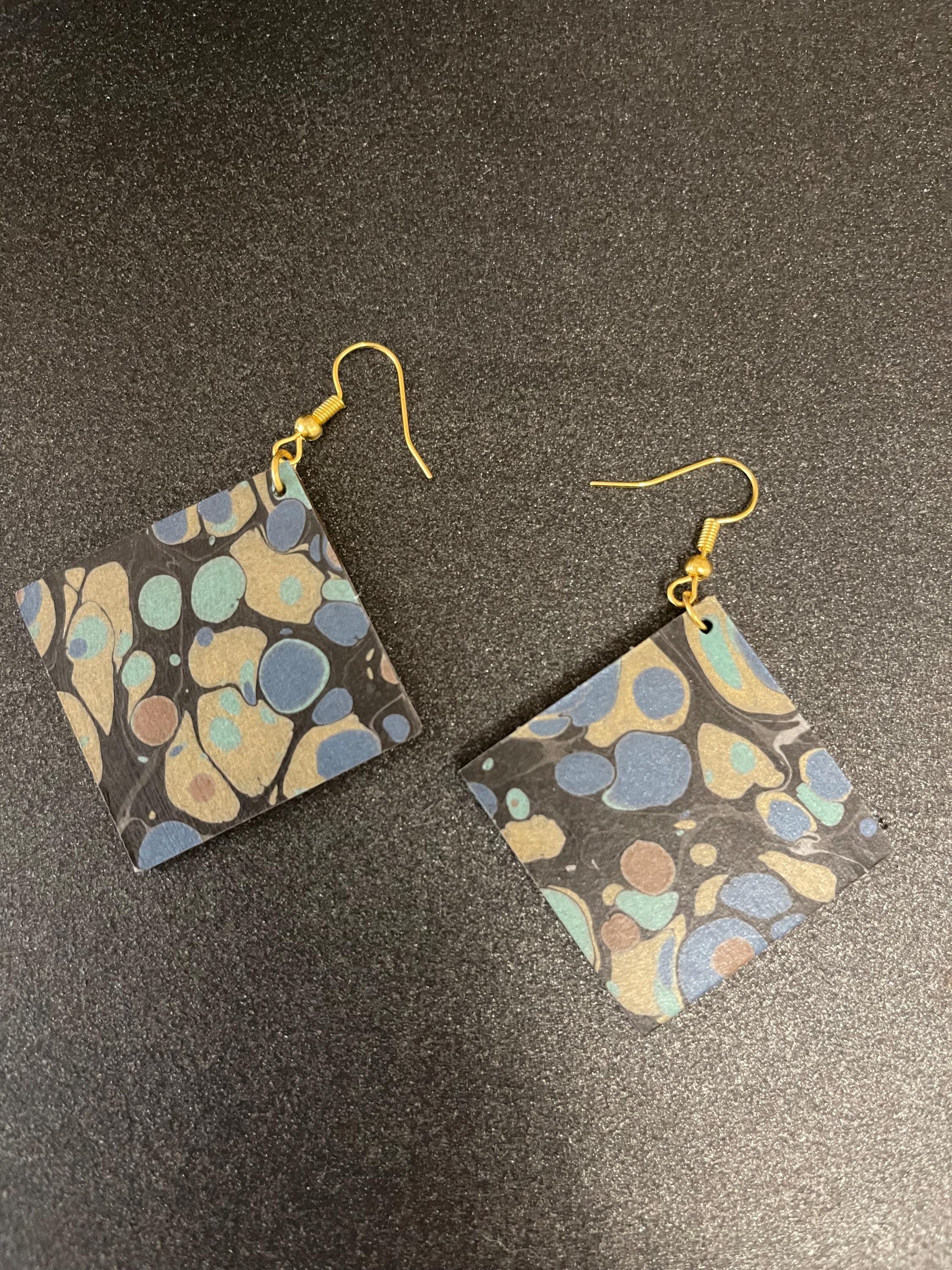 Unique square marbled dangle earrings with gold hyper allergenic hooks, stone pattern in gold, blue and green on a black background