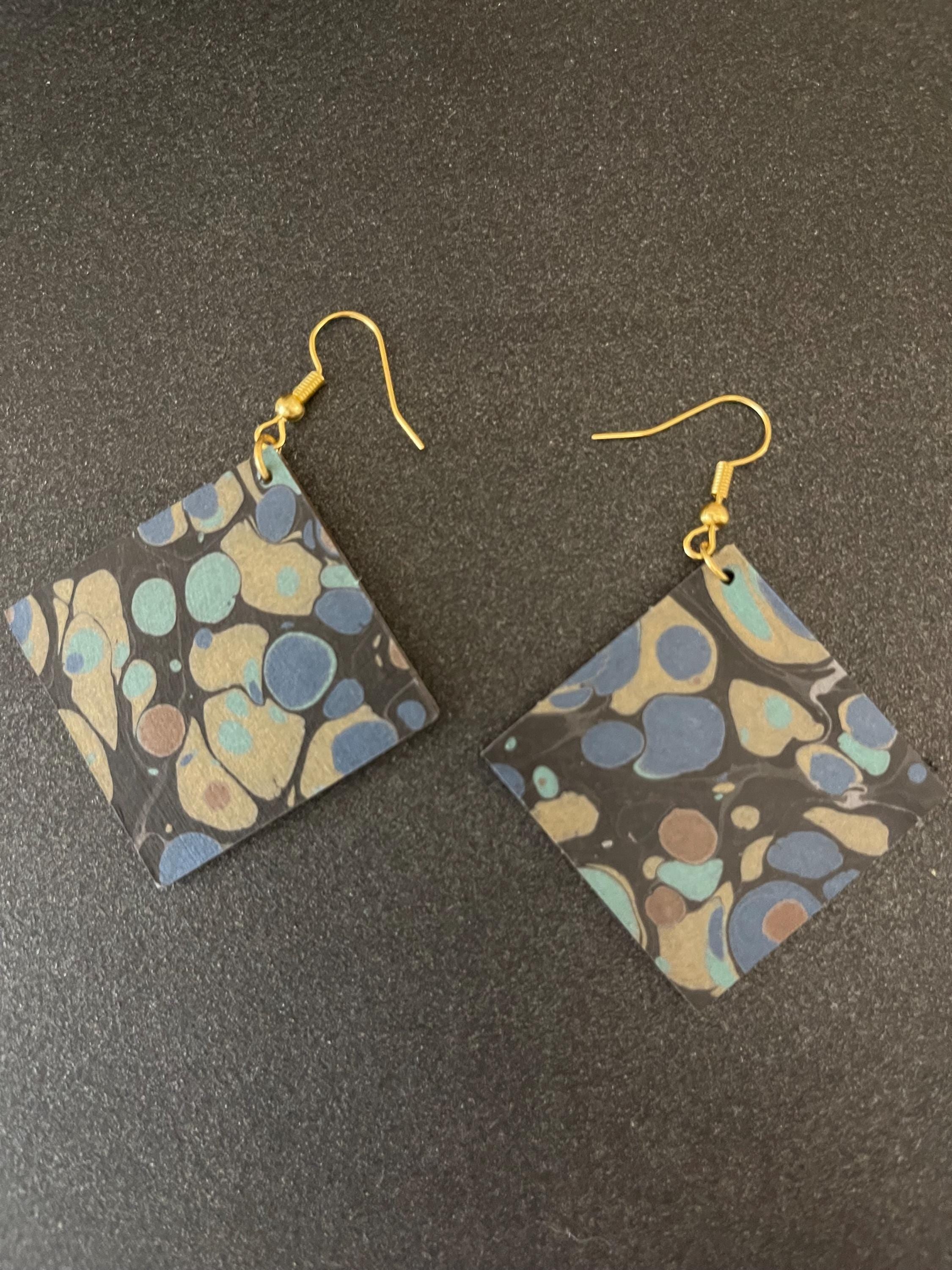 Unique square marbled dangle earrings with gold hyper allergenic hooks, stone pattern in gold, blue and green on a black background