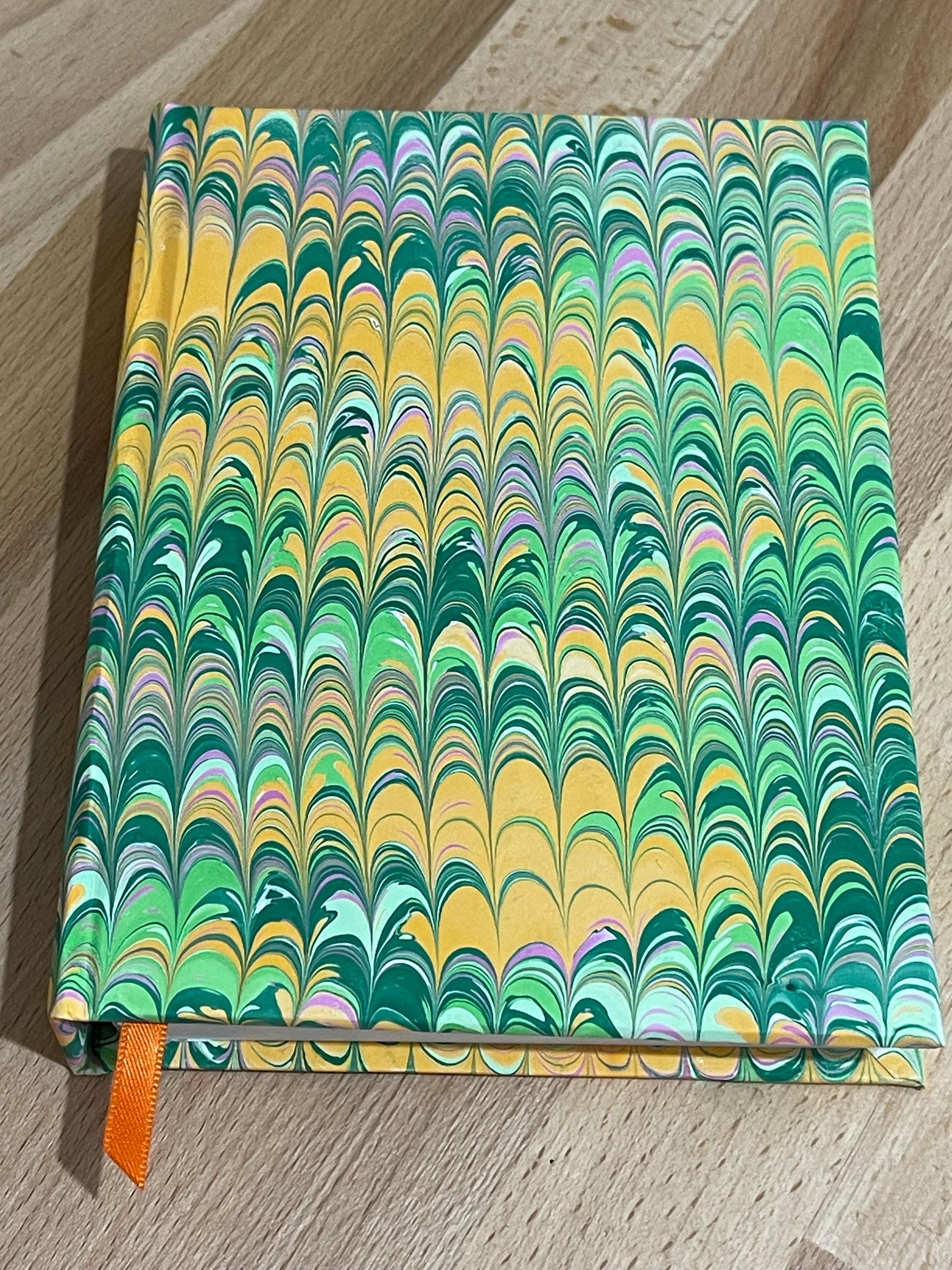 Hand marbled/painted notebook journal in a green and orange non pareil pattern with an orange book mark and recycled white lined pages