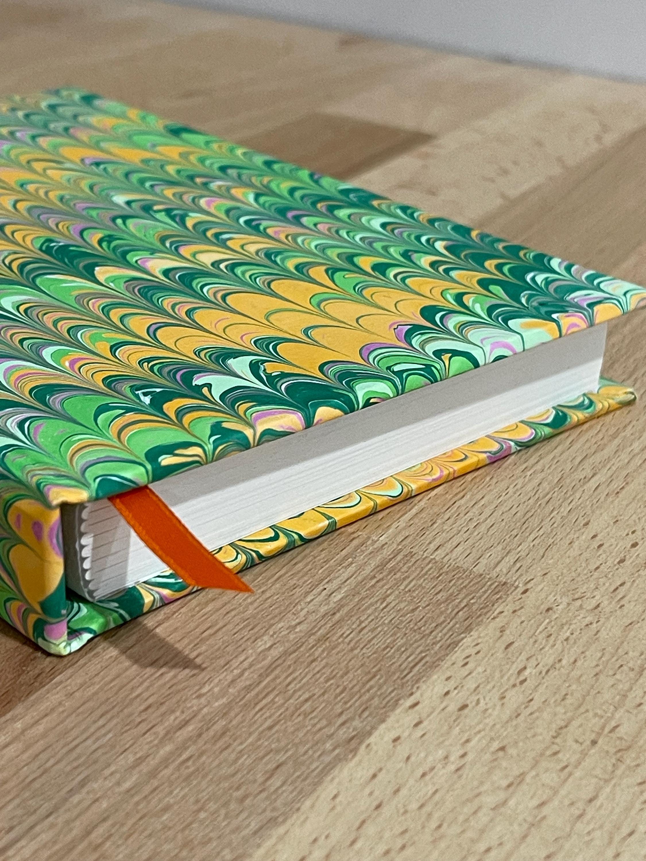 Hand marbled/painted notebook journal in a green and orange non pareil pattern with an orange book mark and recycled white lined pages