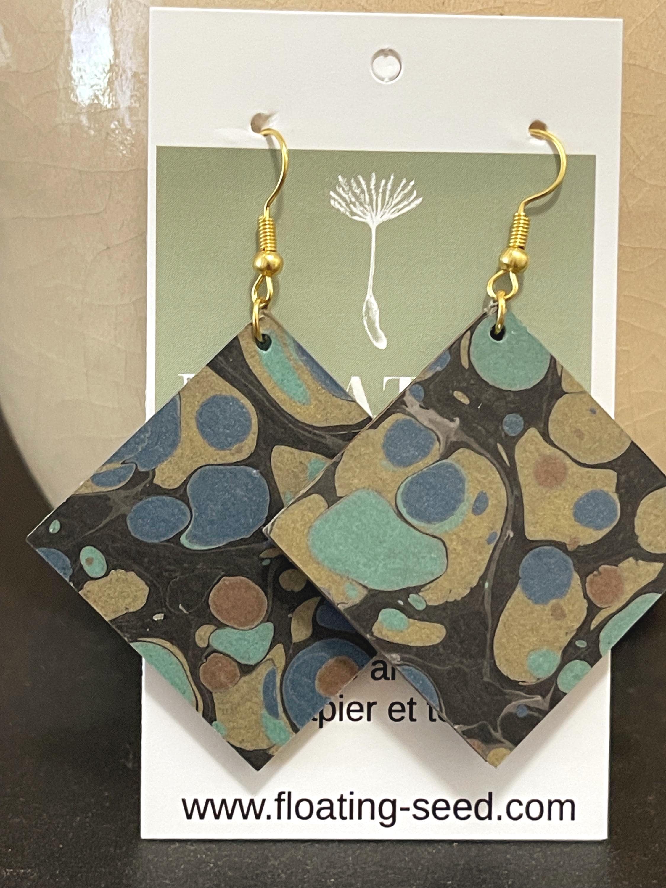 Unique square marbled dangle earrings with gold hyper allergenic hooks, stone pattern in gold, blue and green on a black background